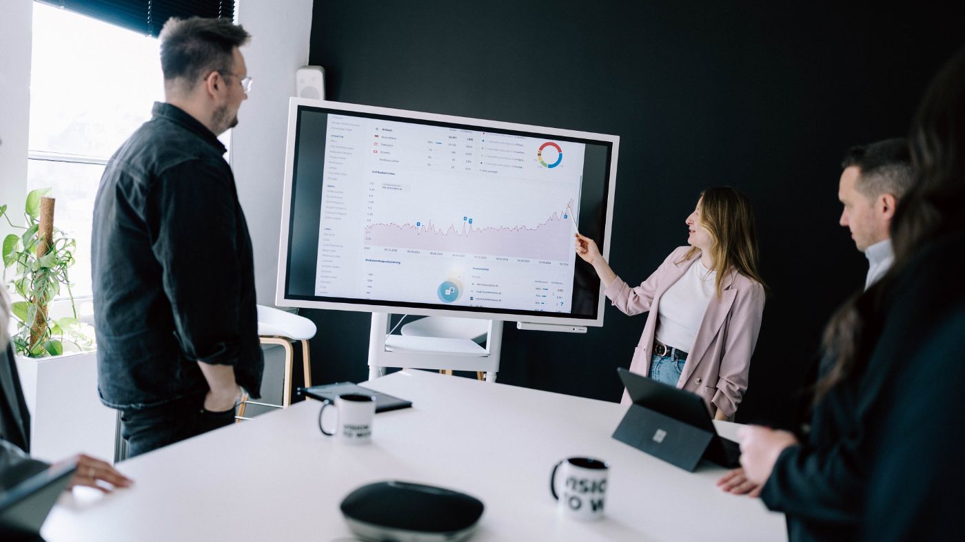 Relaunch Kompetenz Eine Frau steht vor einem Whiteboard und präsentiert eine analytik Grafik.