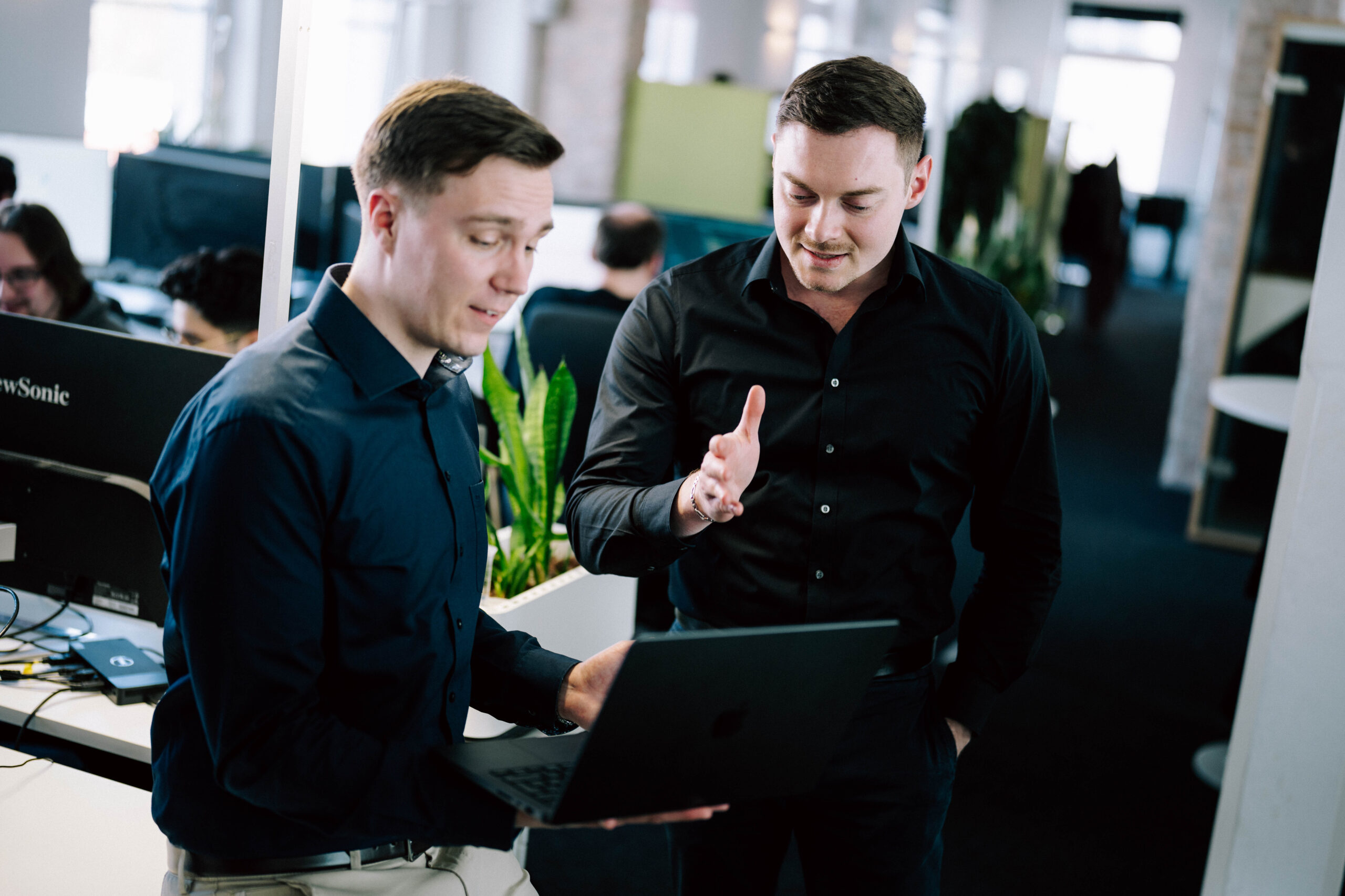 Zwei Männer im Büro besprechen etwas am Laptop.